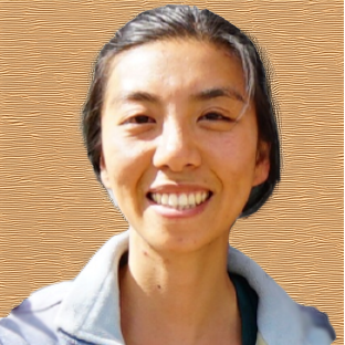 A woman with a smile on her face, wearing a gray shirt.